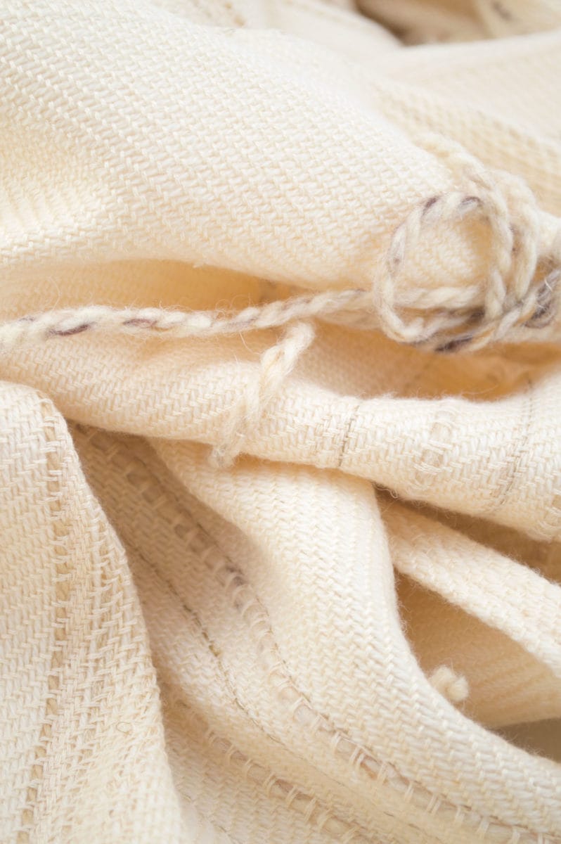 Throw blanket created with pinkish beige silk, ivory cashemeres, unbleached wool, plus a few linen threads and beige cotton slipped into the throw. Graphic wool flowers of beige country, added by hand, after weaving.  Technique: Throw blanket hand-woven in a traditional way on non-mechanical looms in the 7th arrondissement of Paris in France.  Finishes: Right edge. Double stitching.4 pompoms of silk and cashmere of 5,91 inches long.  Size: 55,12 x 66,93 inches.  Single piece / 1 copy only.