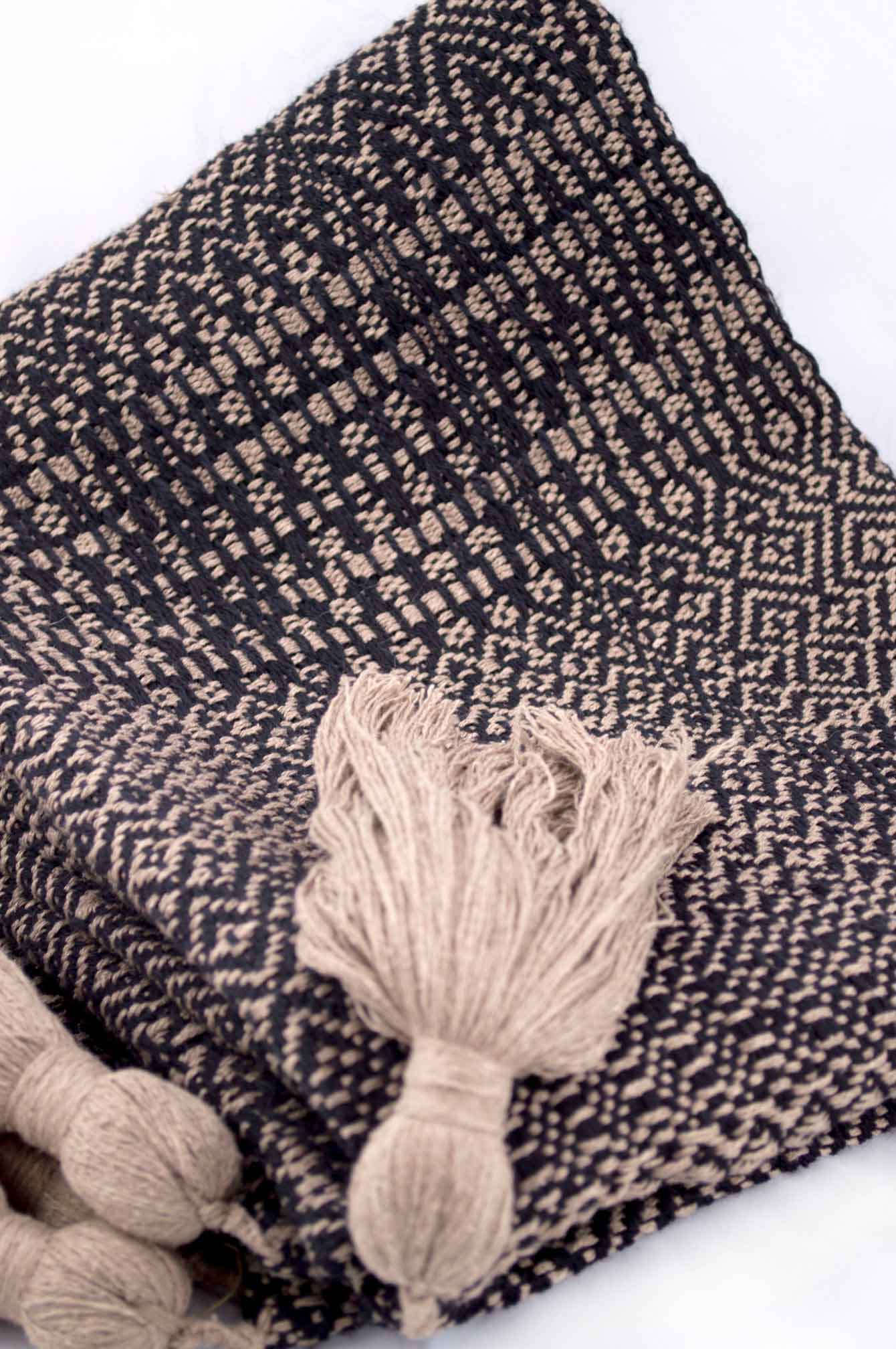 Throw blanket created with sand silk floss, and black wool. Succession of different patterns.  Technique: Throw blanket hand-woven in a traditional way on non-mechanical looms in the 7th arrondissement of Paris in France.  Finishes: Right edge. Double stitching. 4 pompons of 20cm long.  Size: 140 x 200 cm.  Single piece / 1 copy only.