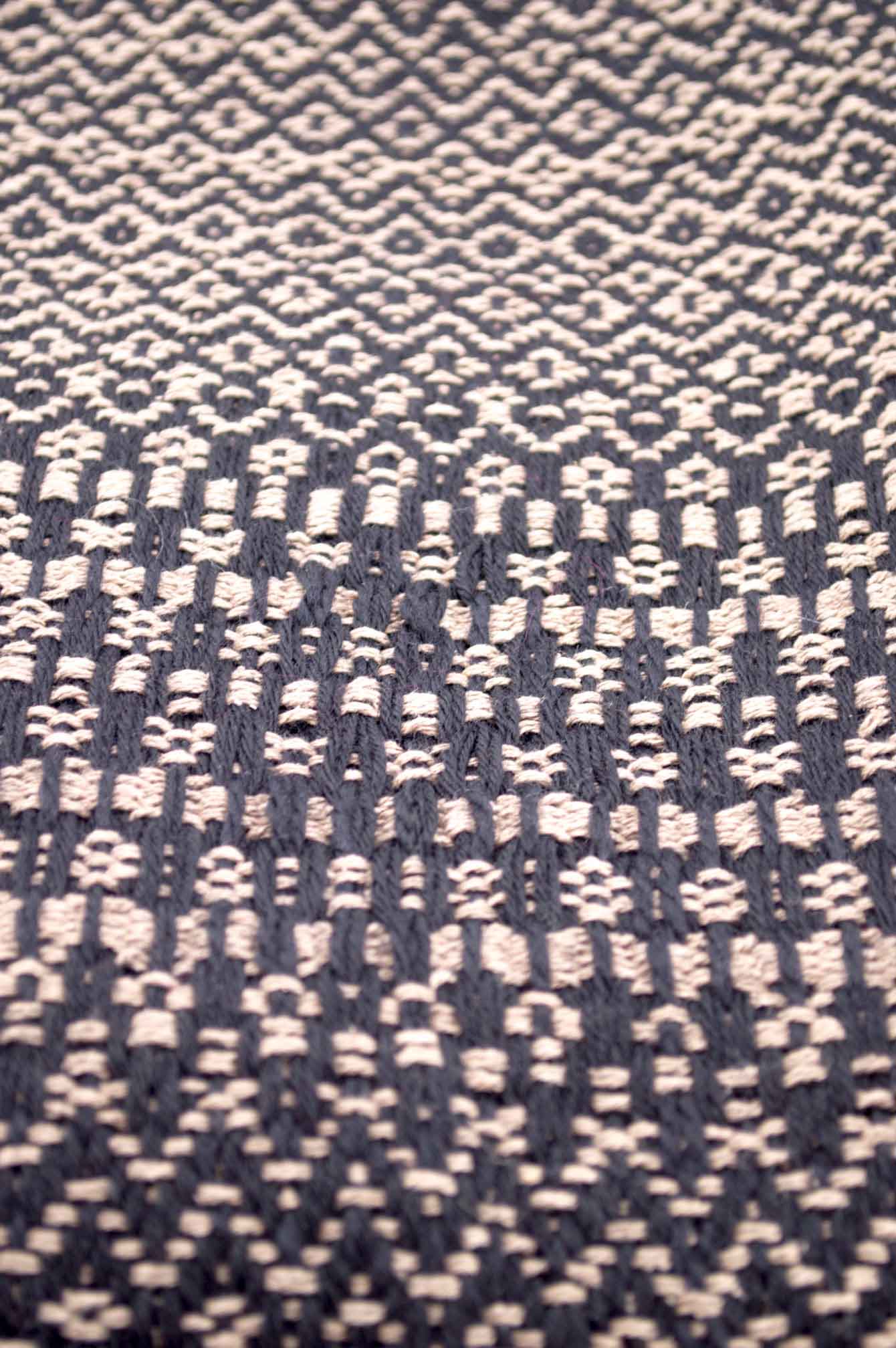 Throw blanket created with sand silk floss, and black wool. Succession of different patterns.  Technique: Throw blanket hand-woven in a traditional way on non-mechanical looms in the 7th arrondissement of Paris in France.  Finishes: Right edge. Double stitching. 4 pompons of 20cm long.  Size: 140 x 200 cm.  Single piece / 1 copy only.