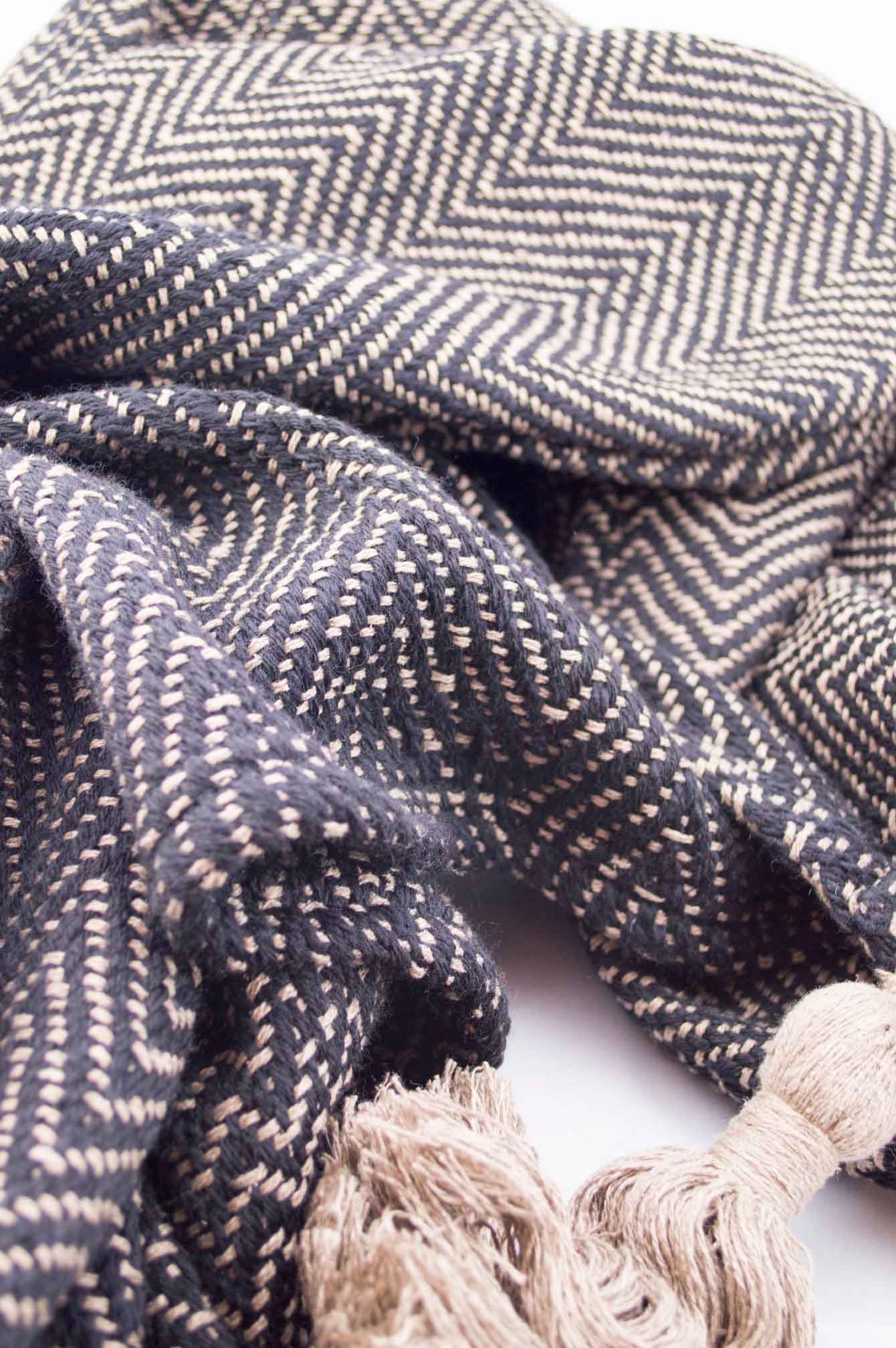 Throw blanket created with sand silk floss, and black wool. Chevrons patterns.  Technique: Throw blanket hand-woven in a traditional way on non-mechanical looms in the 7th arrondissement of Paris in France.  Finishes: Right edge. Double stitching. 4 pompons of 20cm long.  Size: 140 x 190 cm.  Single piece / 1 copy only.