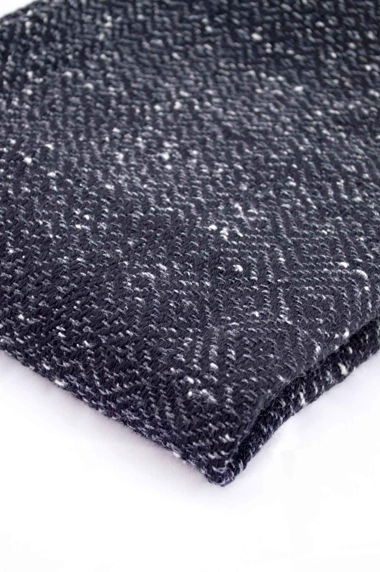 Throw blanket created with dark gray flecked silk floss, black wool. Succession of lozenge patterns.  Technique: Throw blanket hand-woven in a traditional way on non-mechanical looms in the 7th arrondissement of Paris in France.  Finishes: Right edge. Double stitching. 4 pompons 11 cm long.  Size: 140 x 180 cm.  Single piece / 1 copy only.