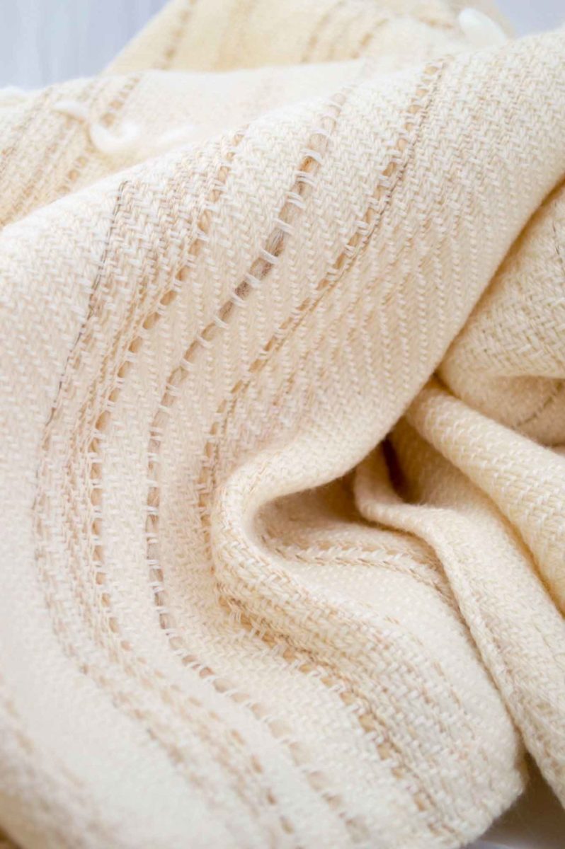 Throw blanket created with white cashmere, ecru wool plus some linen and beige cotton threads slipped into the throw blanket. White wool loop lines added after weaving the piece.  Technique: Throw blanket hand-woven in a traditional way on non-mechanical looms in the 7th arrondissement of Paris in France.  Finishing: Right edge. Double stitching. 4 pompoms 9 cm high. Two tones, beige silk and white cashmere.  Size: 140 x 170 cm.  Single piece / 1 copy only.