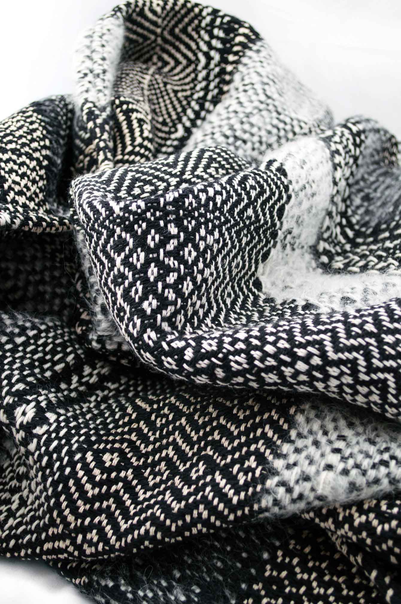 Throw blanket created with ivory mohair, sand silk floss, cashmere, white and black wool. Succession of different patterns.  Technique: Throw blanket hand-woven in a traditional way on non-mechanical looms in the 7th arrondissement of Paris in France.  Finishes: Right edge. Double stitching. 2 edges with 12cm wool fringes.  Size: 135 x 235 cm.  Single piece / 1 copy only.
